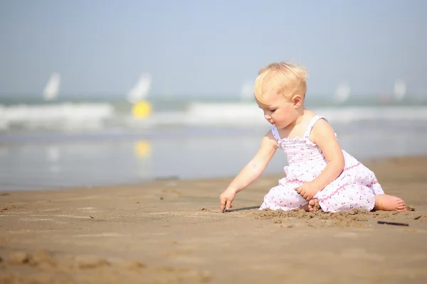 Baby girl drawing creative picture on a sand — Stock Photo, Image