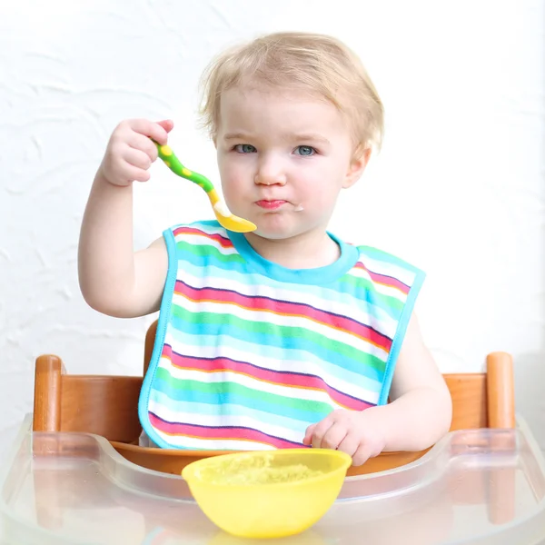 Girl eating porridge with spoon — Stock Photo, Image