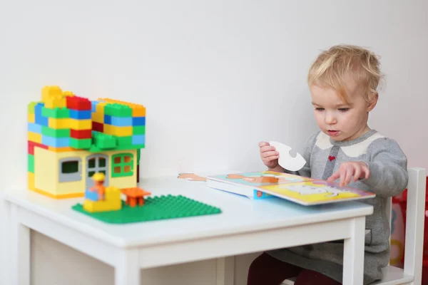 Girl solving puzzles in the book — Stock Photo, Image