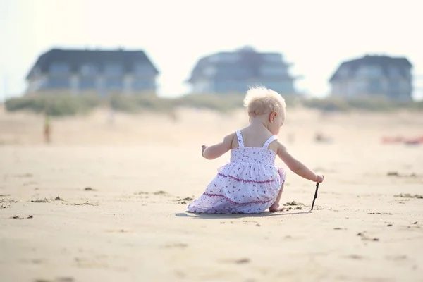 Baby girl drawing creative picture on a sand — Stock Photo, Image