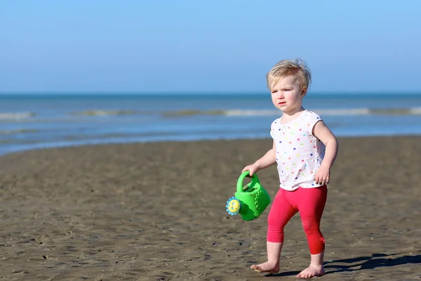 Girl plays with watering can on beach — Stock Photo, Image