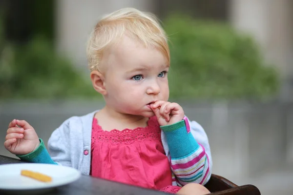 Baby girl biting on tasty french fries — Stock Photo, Image