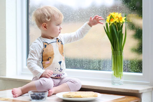 Девушка наслаждается блинчиками, сидя на кухне — стоковое фото