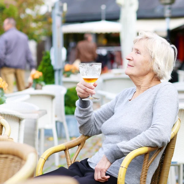 Старшая женщина в кафе пьет холодное свежее пиво — стоковое фото