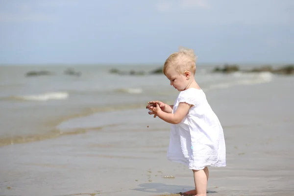 Baby girl walking along the water on the beach — Stock Photo, Image