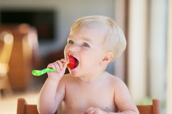 Baby opens her mouth to eat fresh tomato — Stock Photo, Image