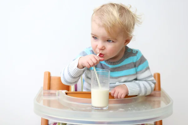 Девушка пьет молоко из стакана с соломой — стоковое фото