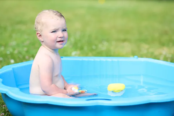 Flicka som leker med vatten i små plast badkar — Stockfoto