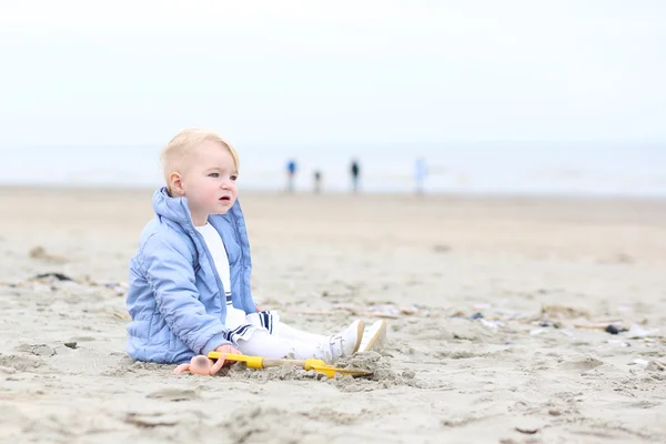 Menina brinca com os brinquedos sentados na praia de areia — Fotografia de Stock