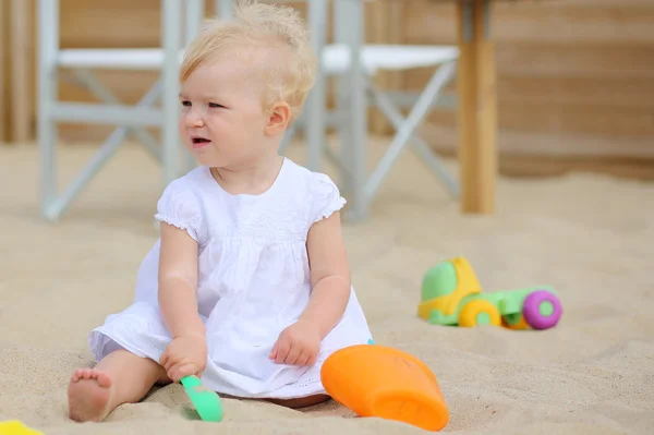 Dziecko dziewczynka gra z zabawkami w piasku na plaży kawiarni — Zdjęcie stockowe