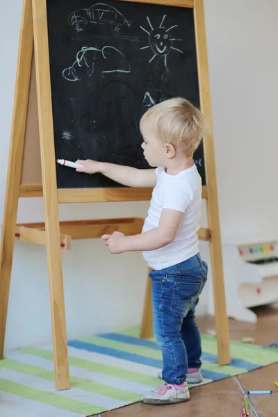 Bebê menina desenho com giz e lápis de cera na placa preta — Fotografia de Stock