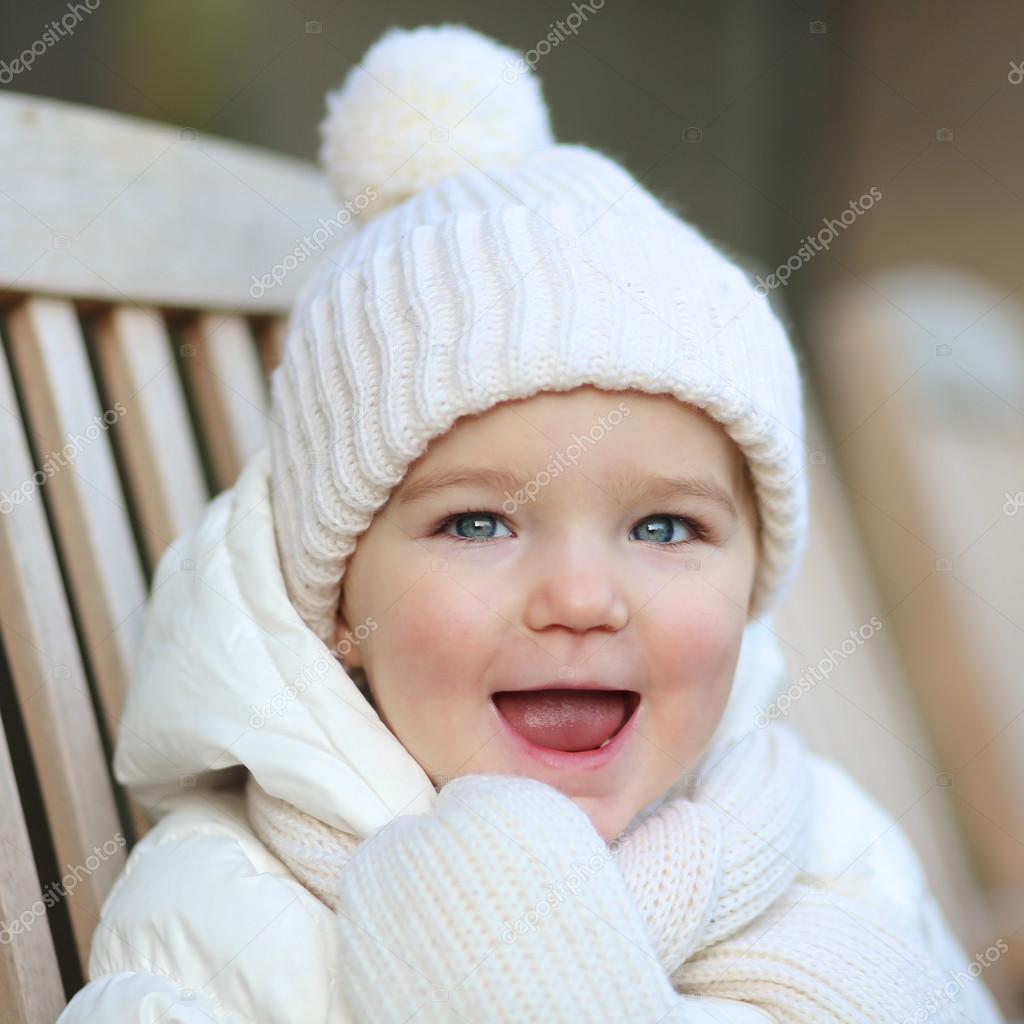 Girl in warm white jacket and knitted hat with scarf