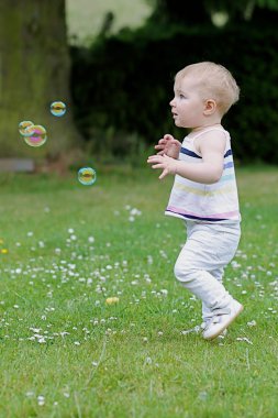 Kız açık havada sabun köpüğü yakalamaya çalışıyor oynuyor
