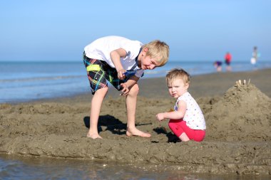 oğlan ve kız kardeşi beraber kumsalda oynarken