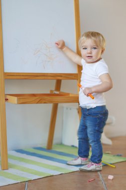 kız bebek mum boya ile bir beyaz tahtaya çizer.