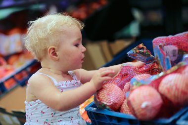 Turuncu sebze ve meyveler bir raf seçme kız bebek