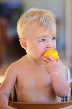 yüksek sandalye üzerinde oturan Ekşi limon yiyen kız