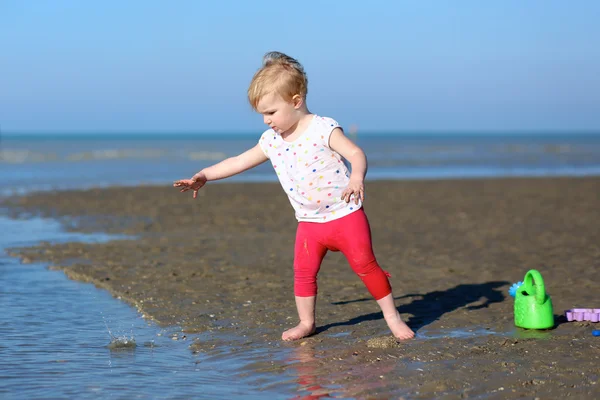 Meisje speelt met gieter op strand — Stockfoto