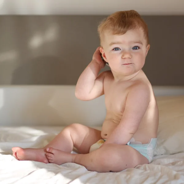 Niedliches Baby sitzt im Bett der Eltern — Stockfoto