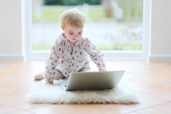 Girl playing with notebook sitting on the tiles floor — Stock Photo, Image