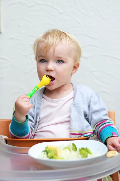 Girl eating boiled vegetables with plastic fork — Stock Photo, Image
