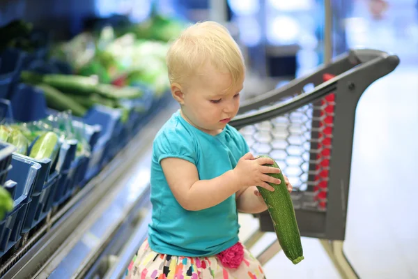 Fille regardant courgettes ramassé à partir d'une étagère — Photo