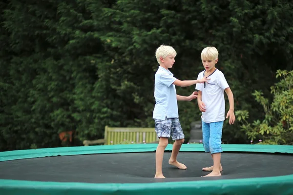 Hermanos jugando juntos al aire libre en un trampolín — Foto de Stock