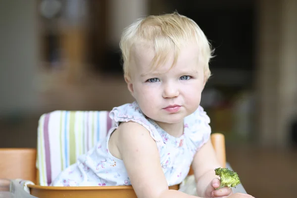 Baby flicka sitter i en hög utfodring stol — Stockfoto