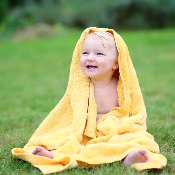 Baby in warmgelbem Handtuch auf dem Gras sitzend — Stockfoto