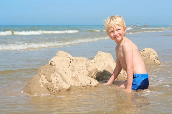 Menino brincando com areia na praia — Fotografia de Stock