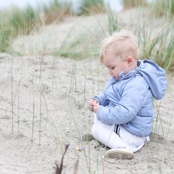 Menina brinca com areia nas dunas — Fotografia de Stock