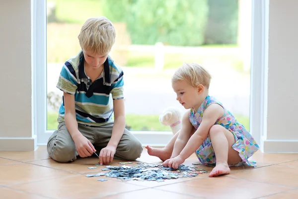 Chica jugando puzzles con su hermano — Foto de Stock