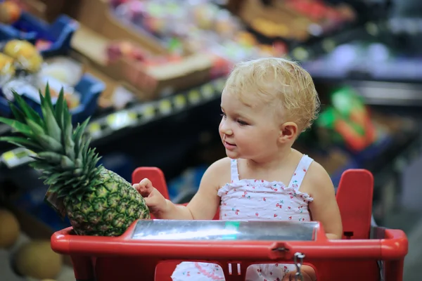 Süpermarkette kırmızı alışveriş sepeti oturuyor ve bebek kız — Stok fotoğraf