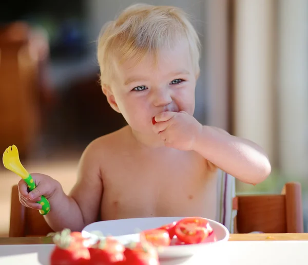 Bébé mords sur une tomate fraîche savoureuse — Photo