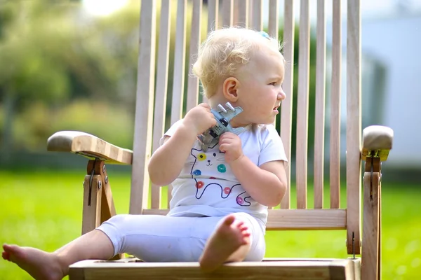 Baby girl sitting on a wooden chair — Stock Photo, Image