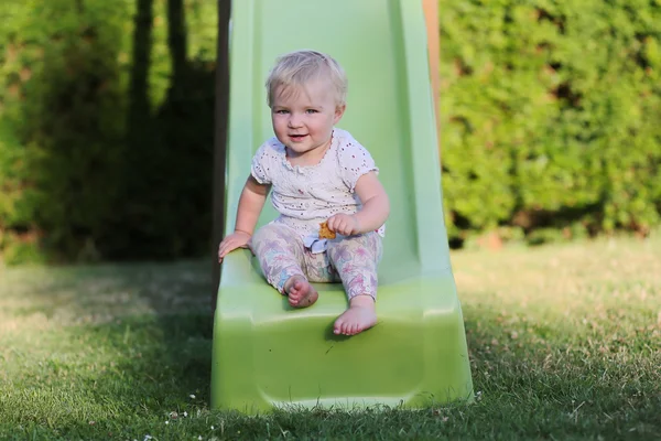 Meisje van de baby spelen op een dia op een park — Stockfoto
