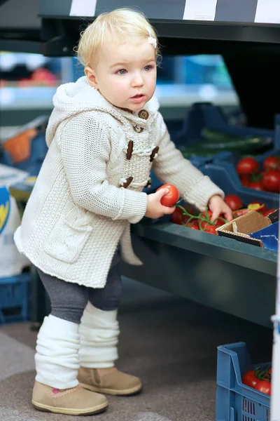 Menina pegando tomate de uma prateleira — Fotografia de Stock