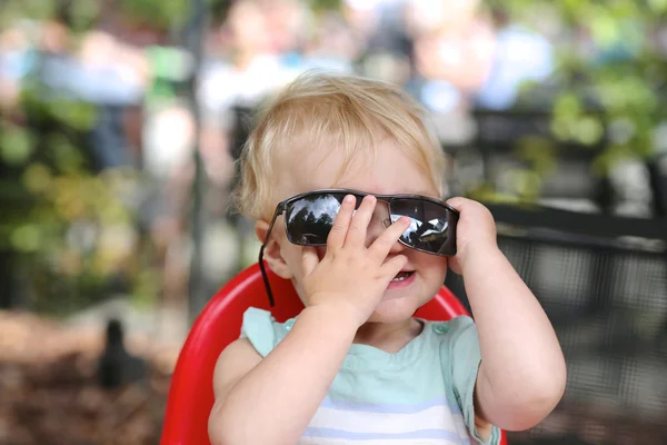 Menina bebê jogando peek um boo atrás de grandes óculos de sol — Fotografia de Stock