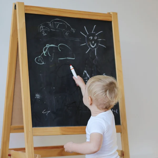 Bebê menina desenho com giz na placa preta — Fotografia de Stock