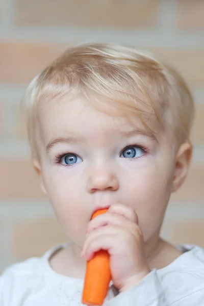 Bebê menina morde deliciosa cenoura crua fresca — Fotografia de Stock