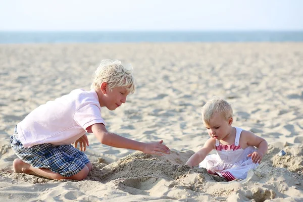 Garçon et sa petite soeur construisant le château de sable — Photo