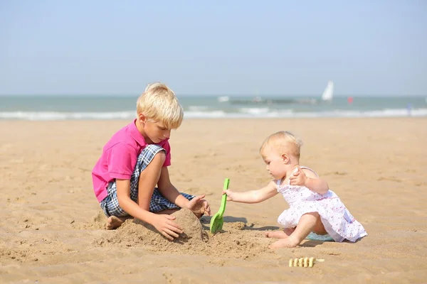 Мальчик и его младшая сестра играют вместе на пляже — стоковое фото