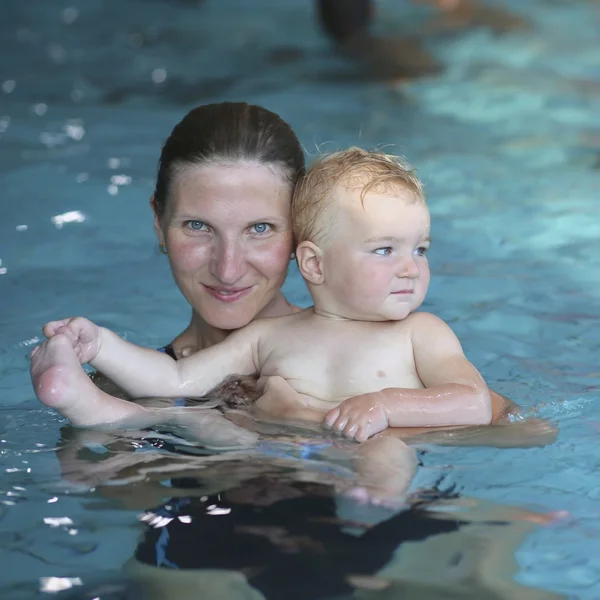 Mãe segurando bebê em uma piscina — Fotografia de Stock