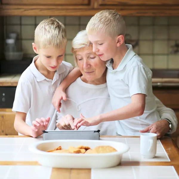 Fratelli insegnare nonna a giocare su tablet pc — Foto Stock
