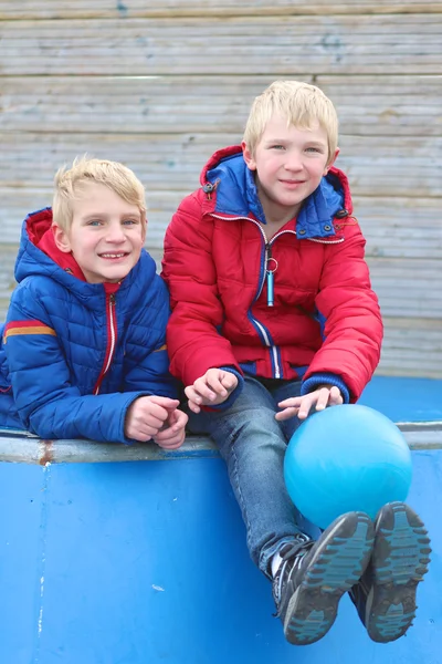 Twin brothers on the playground playing with ball — Stock Photo, Image