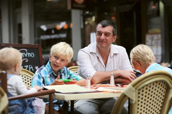 Vader met drie kinderen plezier in café — Stockfoto