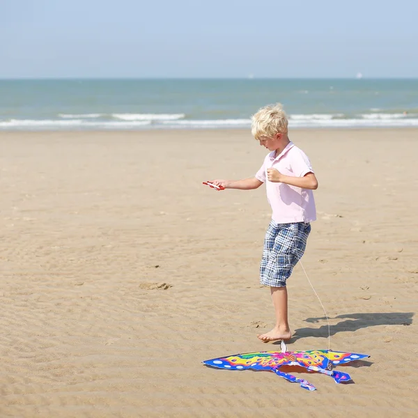 Pojke stående på våt sand på en kust — Stockfoto