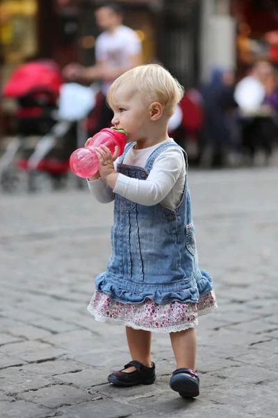 Baby flicka dricksvatten från plast nappflaska — Stockfoto