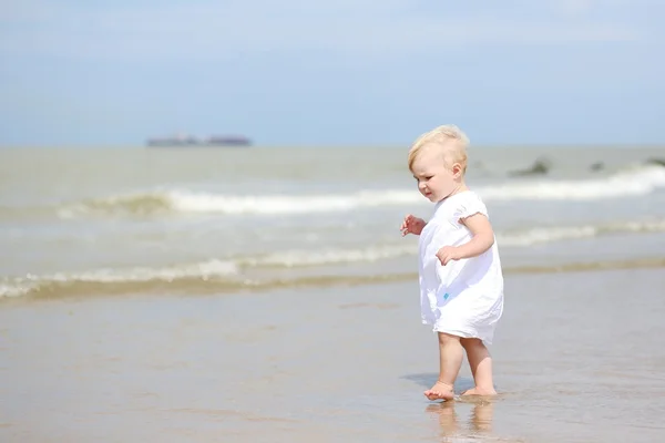 Menina caminhando ao longo da água na praia — Fotografia de Stock