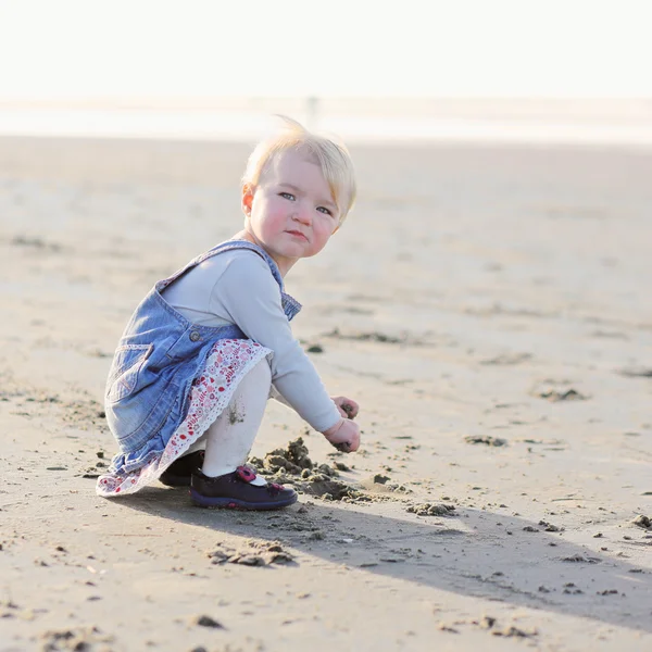 Девочка любит песок, играя на пляже — стоковое фото
